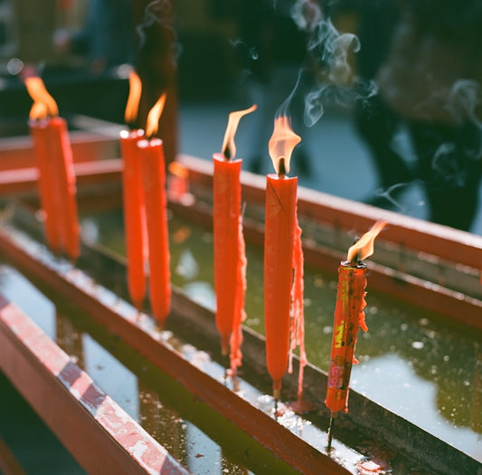a row of lit candles sitting on top of a wooden bench